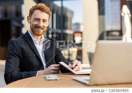 Professional in suit using paper notebook at city cafe Professional in suit using paper notebook at city cafe 130363403