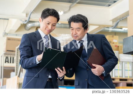 倉庫で会議をするミドルのビジネスマン 130363526