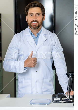 Dark-haired bearded pharmacist in a lab coat looking confident and contented Dark-haired bearded pharmacist in a lab coat looking confident and contented 130363580