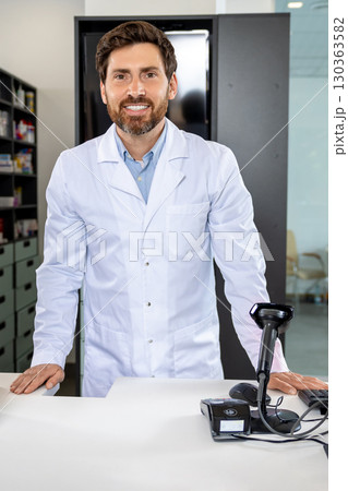 Caucasian man in lab coat standing at the counter in the pharmacy 130363582