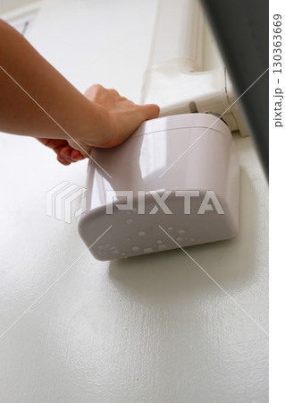 Wall-mounted drain pump for air conditioner with water droplets underneath, indicating malfunction or leakage. 130363669