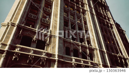 A magnificent building features detailed stonework and architectural elegance, illuminated by bright sunlight. The structure stands tall against a clear sky, capturing attention with its grandeur. 130363946