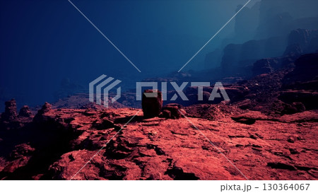 A serene dusk settling over the rugged red cliffs of a canyon under a deep blue sky. 130364067