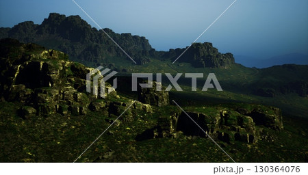 Lush green hills and towering rocky formations dominate the tranquil landscape during twilight. The shadows create a serene and mysterious atmosphere in this remote area. Lush green hills and towering rocky formations dominate the tranquil landscape during twilight. The shadows create a serene and mysterious atmosphere in this remote area. 130364076