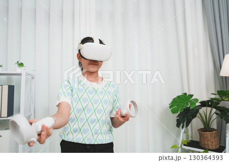 A young girl experiencing the metaverse, using a futuristic VR headset for entertainment at home. 130364393