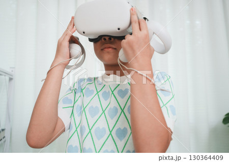 Elementary student learning with VR headset in classroom. Immersive edtech. 130364409