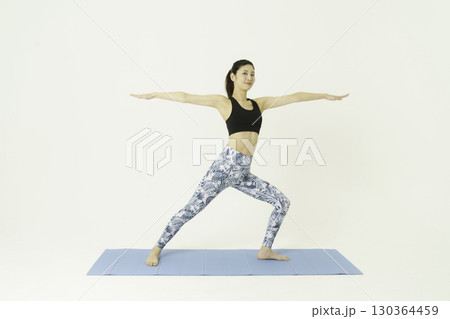 白背景の戦士のポーズをする若い女性　ヨガ 130364459