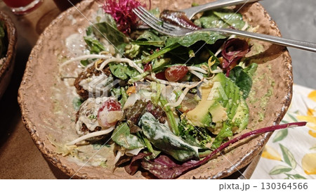 Colorful vegan salad with falafel, avocado, grapes and greens served in a rustic bowl with creamy dressing 130364566