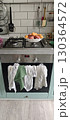 Modern kitchen with a gas stove, utensils hanging on a tiled wall, and a bowl of fresh summer fruits on the counter 130364572