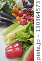Assortment of fresh summer fruits and vegetables including corn, eggplants, berries, tomatoes and greens on a white surface 130364573