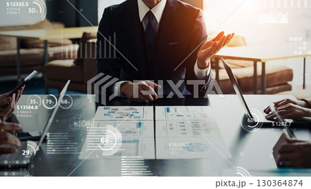 オフィスで会議するビジネスパーソンのグループと統計データのコンセプト オフィスで会議するビジネスパーソンのグループと統計データのコンセプト 130364874