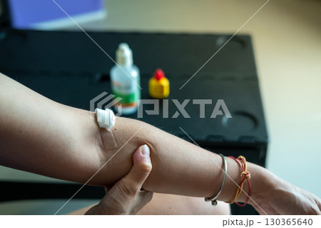 Medical care concept cotton swab pressed on injection wound on Asian woman arm in clinic 130365640