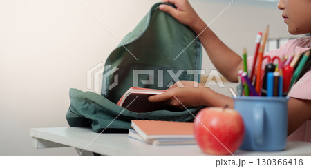 Back to School. Child organizing school supplies in backpack. 130366418