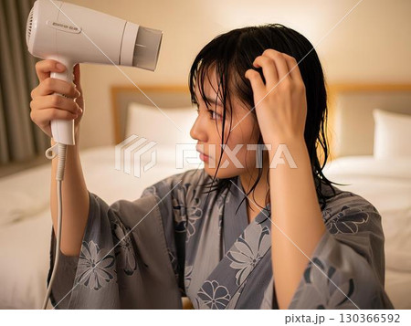 ホテルの部屋でドライヤーで髪を乾かす女性 130366592