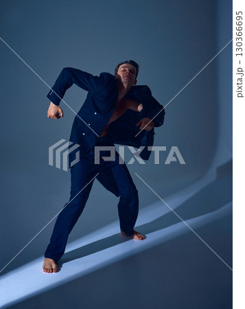 Male dancer moving forward in suit with clenched arms and emotional inner conflict Male dancer moving forward in suit with clenched arms and emotional inner conflict 130366695