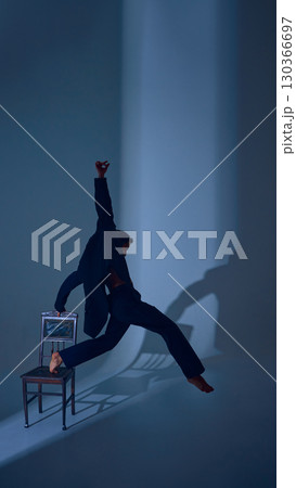 Male dancer stretching upward from chair in suit with extended arm and emotional strength Male dancer stretching upward from chair in suit with extended arm and emotional strength 130366697