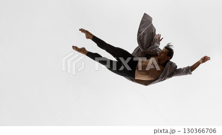 Male dancer floating horizontally in coat with focused gaze and emotional restraint Male dancer floating horizontally in coat with focused gaze and emotional restraint 130366706