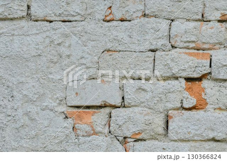 A chipped brick wall. Bricks with remains of plaster. Textured wallpaper. Concept of building and masonry renovation. A chipped brick wall. Bricks with remains of plaster. Textured wallpaper. Concept of building and masonry renovation. 130366824