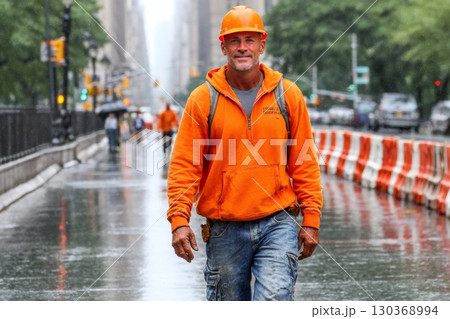 Construction worker walking on rainy city street 130368994