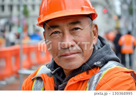 Construction worker wearing orange hard hat and safety vest 130368995