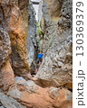 Climber on via ferrata trail, crossing a deep canyon. 130369379