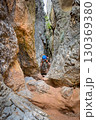 Climber on via ferrata trail, crossing a deep canyon. 130369380