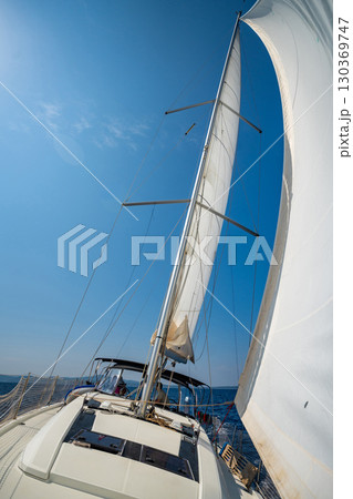 White sails filled with wind, seen from the bow of a sailing yacht near Croatia. Freedom, clean energy, adventure and mindful travel on the open sea. 130369747