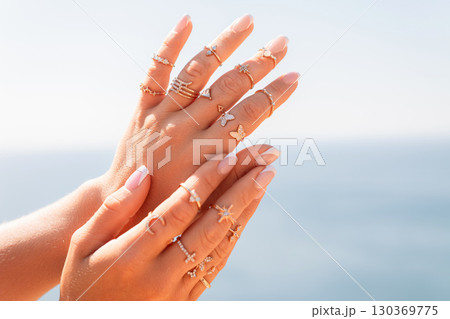 A woman is holding her hands up with a variety of rings on her fingers 130369775