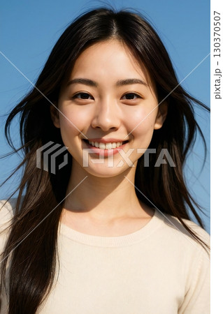 青空の下で微笑み、髪が風に揺れる長髪の美しい日本人女性 130370507