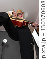 Woman guitarist strumming Spanish six string acoustic guitar, looking at camera. Extraordinary low angle view, wide shot perspective of playful musician. Selective focus on expression female guitarist 130370608