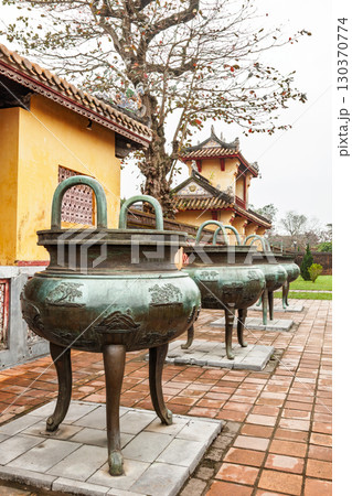 Row of ancient bronze dynastic urns on tiled terrace at Hue Imperial City Vietnam 130370774