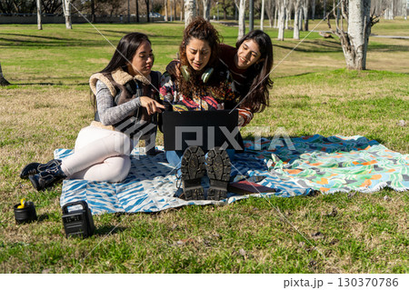 Students working on laptop outdoors in park 130370786