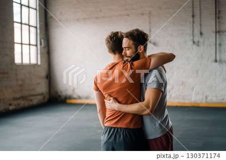 Two men hug each other in a gym 130371174