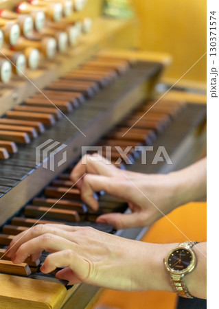 A female musician plays a piece on an antique wooden organ A female musician plays a piece on an antique wooden organ 130371574