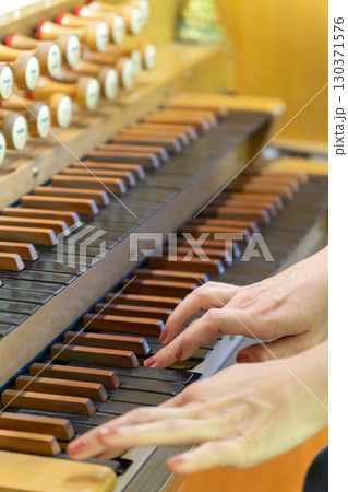 A female musician plays a piece on an antique wooden organ 130371576