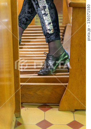 A close-up shot of a musician's foot pressing the pedals of a majestic, antique pipe organ 130371580