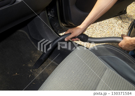 a man vacuums the car floor mat 130371584