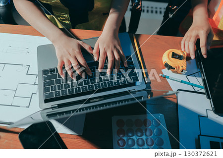 Closeup of team of industrial engineers meeting analyze machinery blueprints consult project on table in manufacturing factory. Working in manufacturing plant or production plant. Closeup of team of industrial engineers meeting analyze machinery blueprints consult project on table in manufacturing factory. Working in manufacturing plant or production plant. 130372621