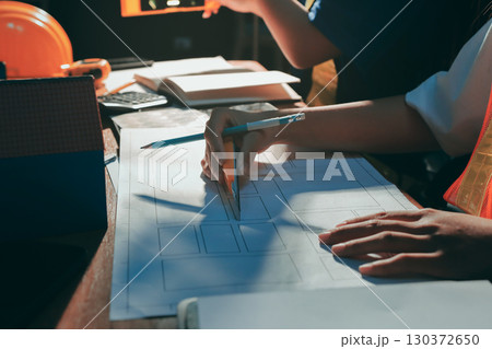 Closeup of team of industrial engineers meeting analyze machinery blueprints consult project on table in manufacturing factory. Working in manufacturing plant or production plant. Closeup of team of industrial engineers meeting analyze machinery blueprints consult project on table in manufacturing factory. Working in manufacturing plant or production plant. 130372650
