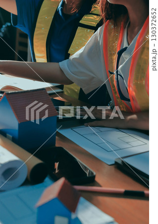 Closeup of team of industrial engineers meeting analyze machinery blueprints consult project on table in manufacturing factory. Working in manufacturing plant or production plant. Closeup of team of industrial engineers meeting analyze machinery blueprints consult project on table in manufacturing factory. Working in manufacturing plant or production plant. 130372652
