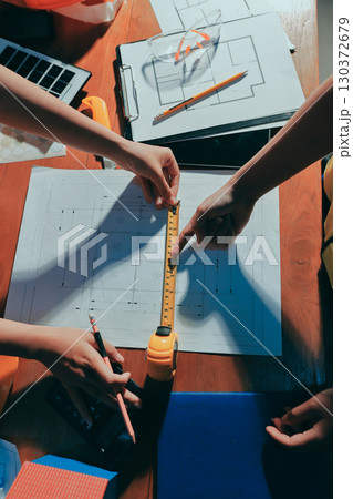 Closeup of team of industrial engineers meeting analyze machinery blueprints consult project on table in manufacturing factory. Working in manufacturing plant or production plant. Closeup of team of industrial engineers meeting analyze machinery blueprints consult project on table in manufacturing factory. Working in manufacturing plant or production plant. 130372679