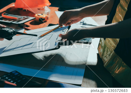 Closeup of team of industrial engineers meeting analyze machinery blueprints consult project on table in manufacturing factory. Working in manufacturing plant or production plant. 130372683