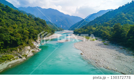 crystal clear river winding through lush green mountains, showcasing pristine nature and clean water conservation 130372778