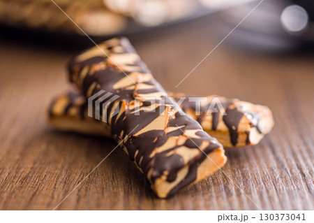 Sfogliatine glassate with chocolate. Italian crispy dessert on wooden table. Sfogliatine glassate with chocolate. Italian crispy dessert on wooden table. 130373041