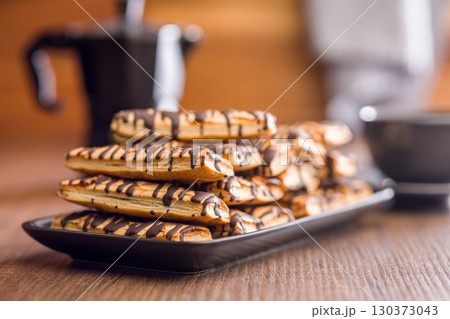 Sfogliatine glassate with chocolate. Italian crispy dessert on plate on wooden table. 130373043