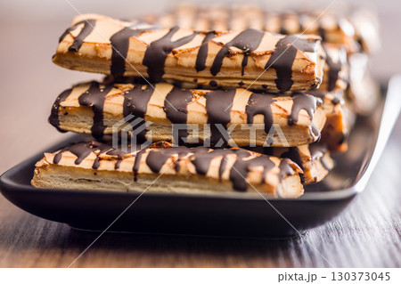 Sfogliatine glassate with chocolate. Italian crispy dessert on plate on wooden table. 130373045