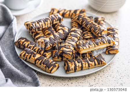 Sfogliatine glassate with chocolate. Italian crispy dessert on plate on kitchen table. Sfogliatine glassate with chocolate. Italian crispy dessert on plate on kitchen table. 130373048