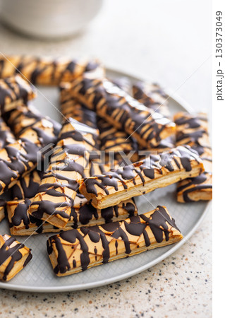 Sfogliatine glassate with chocolate. Italian crispy dessert on plate on kitchen table. Sfogliatine glassate with chocolate. Italian crispy dessert on plate on kitchen table. 130373049