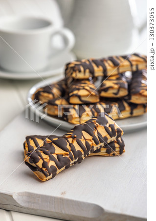 Sfogliatine glassate with chocolate. Italian crispy dessert on white table. Sfogliatine glassate with chocolate. Italian crispy dessert on white table. 130373055