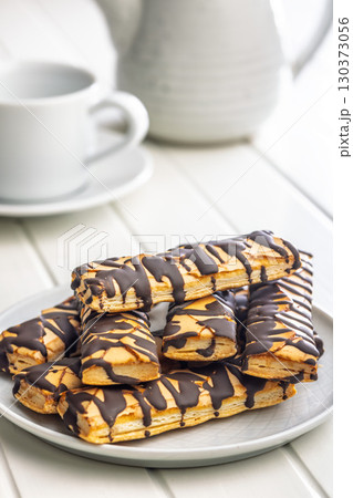 Sfogliatine glassate with chocolate. Italian crispy dessert on plate on white table. Sfogliatine glassate with chocolate. Italian crispy dessert on plate on white table. 130373056